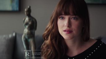 The black sweater with studs of Anastasia Steele (Dakota Johnson) in Fifty shades lighter