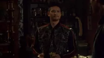Le bomber noir avec bandes latérales rouges porté par Magnus Bane (Harry Shum Jr.) dans Shadowhunters S03E01