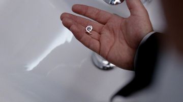 Le pin's "Q" de l'organisation "Quantum" dans Quantum of Solace