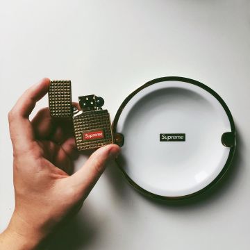 El zippo supremo dorado sostenido en sus manos por el youtuber Vladislav Kirillov en su cuenta de instagram