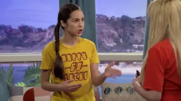 The yellow t-shirt "Happy go lucky" worn by Paige Olvera (Olivia Rodrigo) in Bizaardvark S03E05