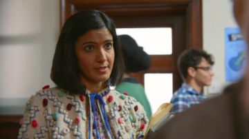 Miss Sands' (Ra­khee Tha­krar) top with wool pom poms as seen in Sex Edu­ca­tion S01E03