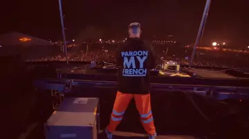 DJ Snake wears neon orange construction pants during a DJ set in YouTube video SUMMER 2018 (Official Recap Video)