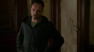 Sudadera con capucha Dry StretchUniqlo Zip Up en gris oscuro usada por Sherlock Holmes (Jonny Lee Miller) en Primaria (S05E03)