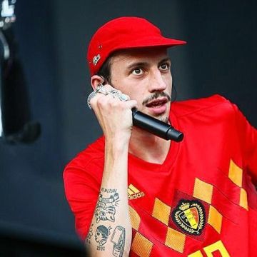 La casquette rouge logo vert Lacoste portée par Roméo Elvis en concert