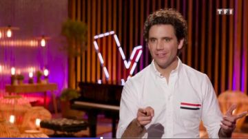 El borde tricolor de la camisa blanca y el parche del logotipo en la parte frontal de Mika en The Voice: la voz más hermosa del 25.04.2019