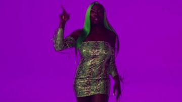 El mini vestido verde con hombros desnudos estampado de serpiente de Aya Nakamura en el clip de cinta Je m'en de Oboy feat. Dopebwoy