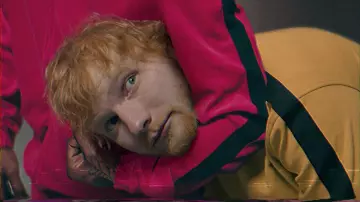Sudadera con capucha amarilla con una tira negra en el brazo usada por Ed Sheeran en el video musical antisocial de Travis Scott