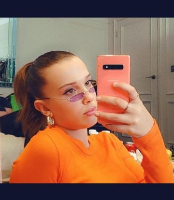 The long sleeve top neon orange worn by Millie Bobby Brown on the account Instagram of @milliebobbybrown