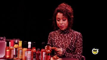 Cheetah sheer turtleneck top of Liza Koshy in Liza Koshy Meets Her Future Self While Eating Spicy Wings | Hot Ones