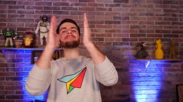 Le pull gris avec un avion coloré de Amixem dans sa vidéo YouTube DEVINEZ LE BON PERSONNAGE DE DESSIN ANIMÉ ! #1