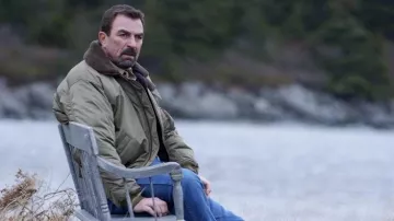 Chaqueta bomber verde con cuello de piel y parche americano usado por Jesse Stone (Tom Selleck) como se ve en Stone Cold