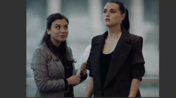 Long black / dark gray coat up to the calf. The entire room has herringbone or checkerboard designs of Saskia De Merindol (Katie McGrath) in Secret Bridesmaids' Business (S01E02)