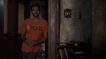 Camiseta con el logotipo de Atari Pong en naranja usada por Jay (Utkarsh Ambudkar) como se ve en el vestuario de la serie de televisión Ghosts (S01E02)