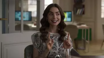 La blouse imprimée Agnès b. "rue du jour" portée par Emily Cooper (Lily Collins) dans Emily in Paris (Saison 2 Épisode 10)