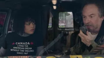 T-shirt « Canada Linving The American Dream Without the Violence since 1967 » porté par Reilly Clayton (Lydia West) dans The Pentaverate (S01)