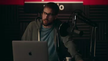 Sudadera con capucha gris con cremallera usada por Josh Carter (Dustin Milligan) como se ve en el vestuario del programa de televisión Rutherford Falls (Temporada 2 Episodio 1)