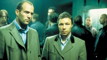 La chemise à carreaux bleue portée par Tur­kish (Jason Statham) dans le film Snatch, tu braques ou tu raques 