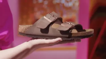 Sandalias Birkenstok sostenidas por Barbie (Kate McKinnon) en Barbie