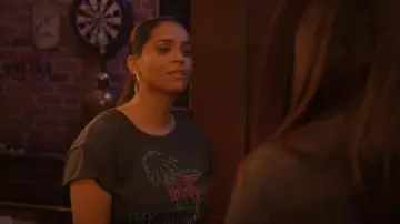 Midnight Rider Twin Palms Ho­tel Graph­ic Tee worn by Liv (Lilly Singh) as seen in Dollface (S02E03)