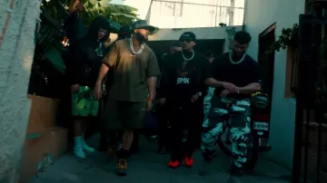 Pantalones cortos de chándal con el logotipo del espacio marrón y amarillo de Helmut Lang usados por El Alfa en TACATA (REMIX) por Tiagz X Fuerza Regida X El Alfa [Video oficial]