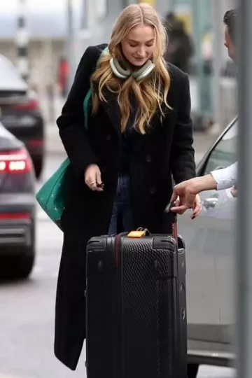 Manteau asymétrique en laine mélangée All Saints Sonnie porté par Sophia Turner à l’aéroport de Londres le 12 janvier 2024