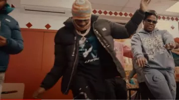 Take Risks & Prosper Black & Grey-Hood Puffer Jack­et worn by Russ in Russ Millions x Fivio Foreign- Canarsie (Official Video)