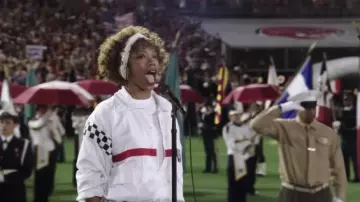 I Wanna Dance With Somebody outfits: Whitney Houston (Naomi Ackie)) is wearing White zip tracksuit to sing the American anthem in the movie