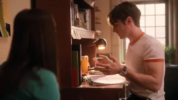 Les looks de The Sex Lives of College Girls : Eli (Michael Provost) porte un t-shirt blanc à bordures oranges dans l'épisode 3 de la saison 3