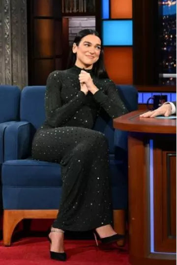 Amina Muaddi Ursina Talons en satin noir portés par Dua Lipa au Late Show with Stephen Colbert le 11 décembre 2024