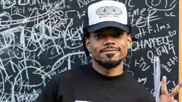 T-shirt graphique noir Chance The Rapper porté par lui-même (Chance The Rapper) tel qu’on le voit dans Chance the Rapper’s Magnificent Coloring World