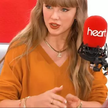 Pull orange à col en V Heart Radio porté par Taylor Swift