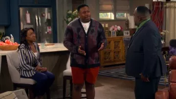 Cardigan Dio de John Varvatos en ciruela oscura llevado por Marty Butler (Marcel Spears) como se ve en The Neighborhood (S08E06)