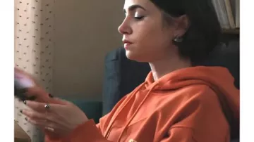 Emily à Paris S5 Lily Collins Sweat à capuche orange avec slogan porté par Emily Cooper (Lily Collins) dans Emily à Paris