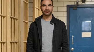 Chaqueta negra Brett Goldstein de Office Romance 2026 llevada por Daniel Blanchflower (Brett Goldstein) tal como se ve en Office Romance