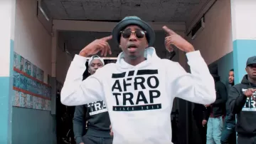 La sudadera con capucha blanca Afro Trap usada por MHD en su video musical de Roger Milla