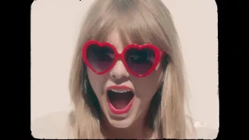 The glasses in the shape of a red heart of Taylor Swift in the clip 22