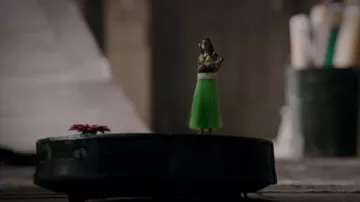 The figurine Hula Dancer with his ukulele mounted on the robot vacuum cleaner in Deadpool (Ryan Reynolds in Deadpool