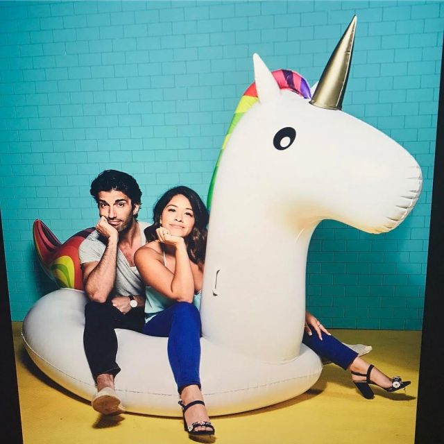 The buoy unicorn giant swimming pool, on which are seated Gina Rodriguez and Justin Baldoni on Instagram