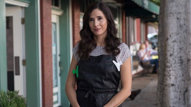 Blusa de estampado de guepardo púrpura usada por Raina (Michaela Watkins) en The House