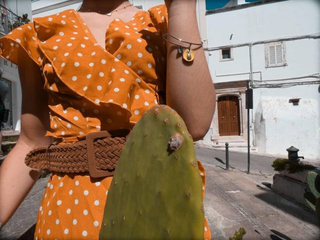 Woman bangle model in silver-colored steel with enameled coin charm and pineapple symbol of Ilaria Nicotra on the Instagram account @ilary_nicotra