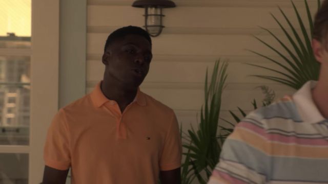 Tommy Hilfiger orange polo shirt porté par Kelce (Deion Smith) comme on le voit dans les Outer Banks (S01E07)