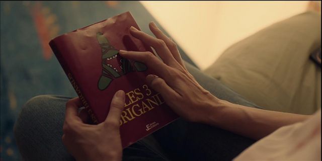 The book Les trois brigands in French held by Déa Versini (Carole Weyers) that belongs to her son in Double Je season 1 episode 4