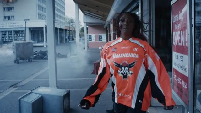 The t-shirt orange hockey jersey Balenciaga worn by Aya Nakamura in the clip C&#39;est Cuit de Major Lazer (feat. Aya Nakamura &amp; Swae Lee)