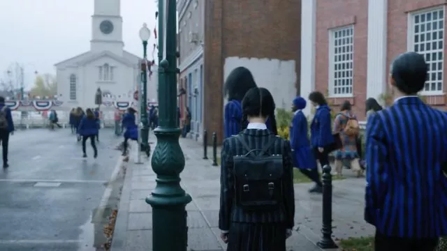 Le sac à dos The Cambridge Satchel Co. porté par Wednesday Addams (Jenna Ortega) dans la série Mercredi (Saison 1 Episode 3)