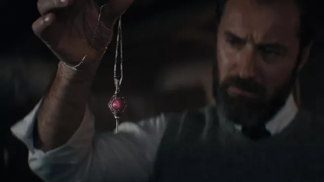 Pendentif collier de pierre rose tenu par Albus Dumbledore (Jude Law) dans le film Les Animaux fantastiques: Les secrets de Dumbledore