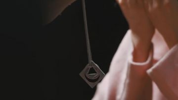 The pendant of the silver necklace in the clip Waves of Dean Lewis