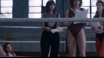La combinaison noire / pantalon à bretelles de Justine Biagi (Britt Baron) dans GLOW (S01E03)