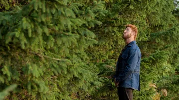 Chaqueta larga de mezclilla usada por Mad Sweeney (Pablo Schreiber) como se ve en los atuendos de los programas de televisión de American Gods (Temporada 1 Episodio 7)