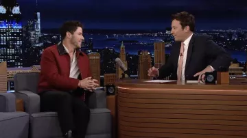 Chaqueta roja con cuello de cuero negro usada por Nick Jonas como se ve en The Tonight Show Starring Jimmy Fallon el 17 de mayo de 2022